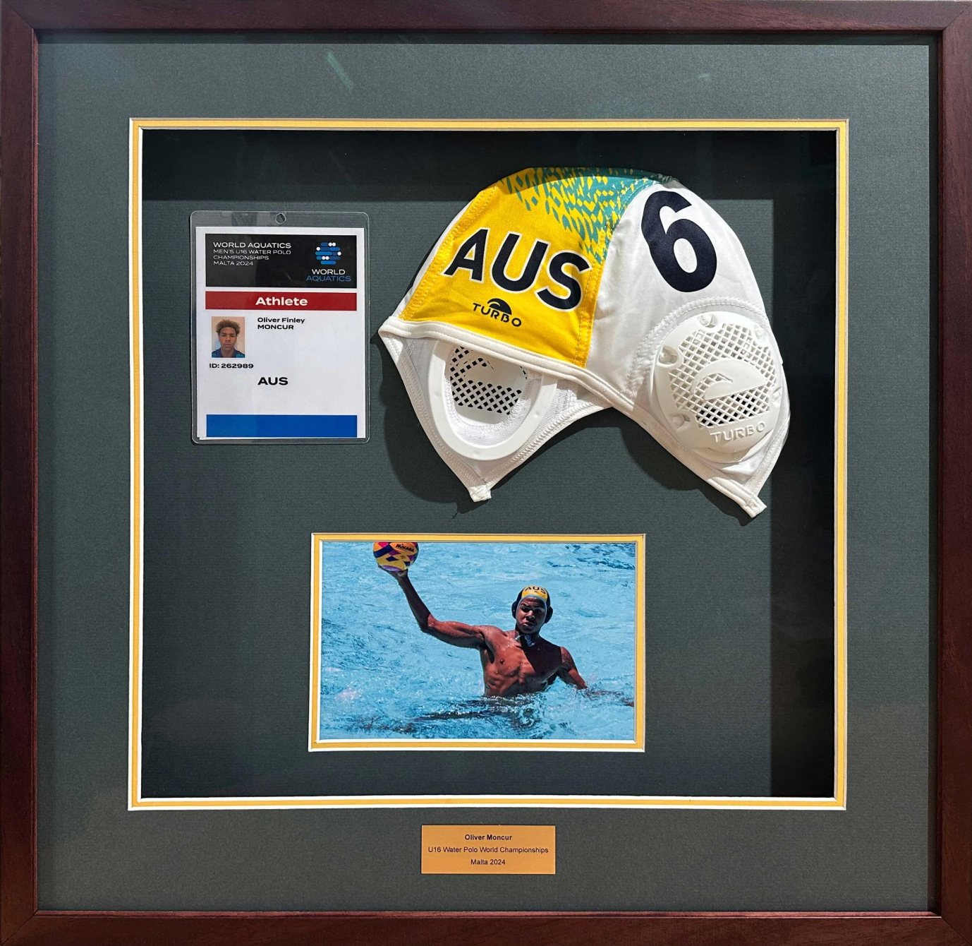 Framed display of a swimmer's cap and photo with an athlete's ID card, featuring the letter 'AUS'.